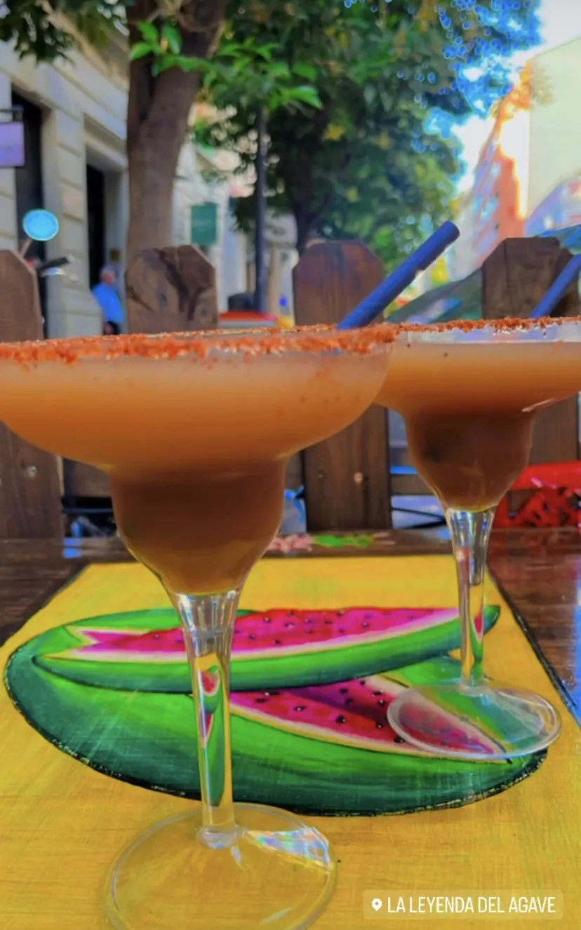 Two frozen margaritas with salted rims on a watermelon-shaped tray