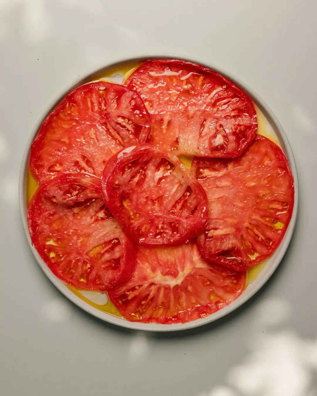 Overhead view of sliced heirloom tomatoes drizzled with olive oil on a plate