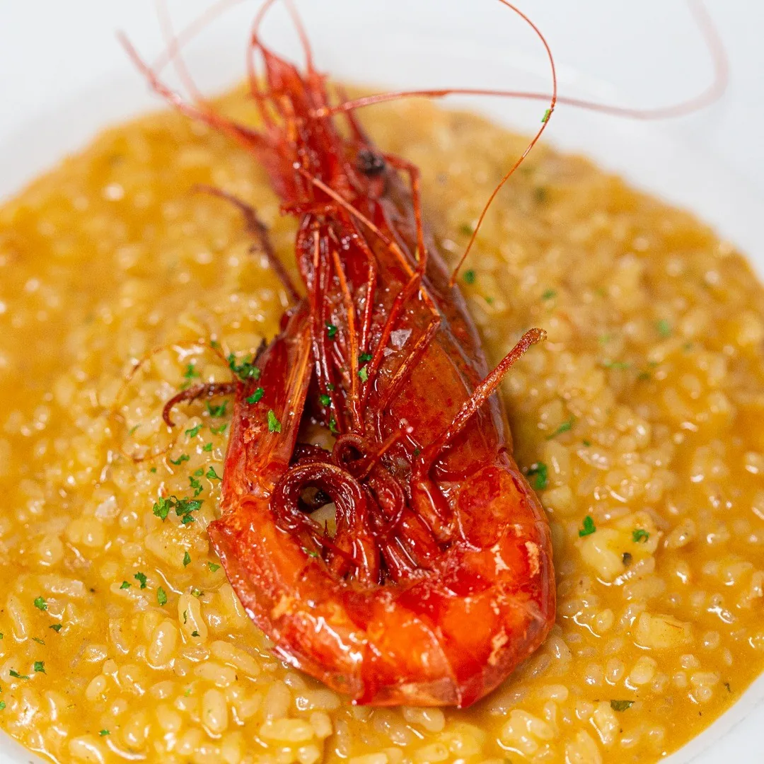Orange rice topped with a whole red prawn