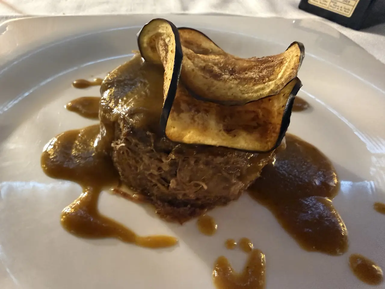 Plated shredded braised meat with gravy and grilled eggplant slices on top