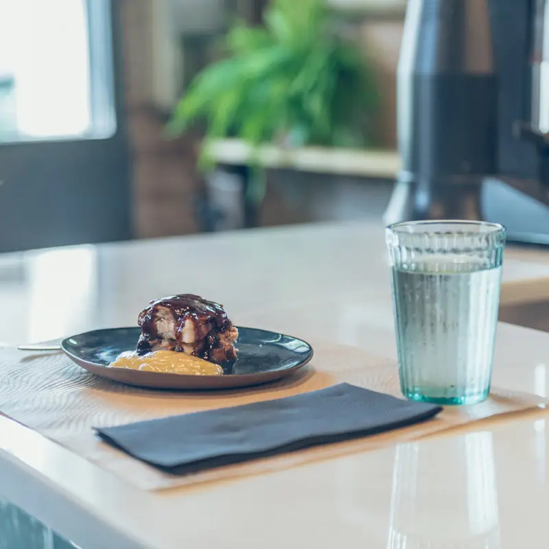 A plated dish of glazed pork rib pieces with a rich dark sauce, served alongside a scoop of mashed potato on a dark ceramic plate, La Marcelina
