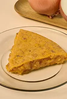 Single wedge of runny Spanish potato tortilla on a clear glass plate