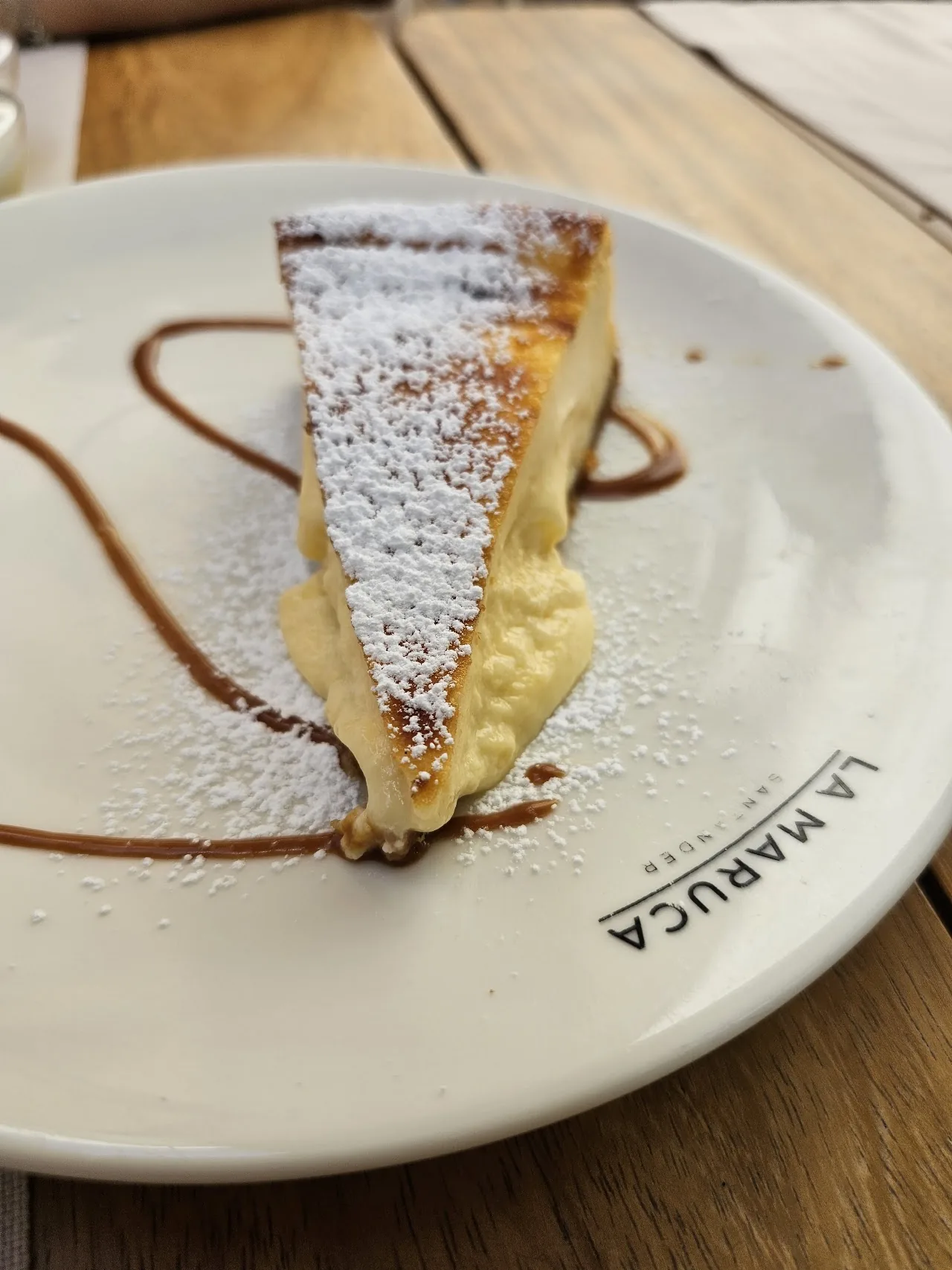 A slice of cheesecake dusted with powdered sugar on a plate