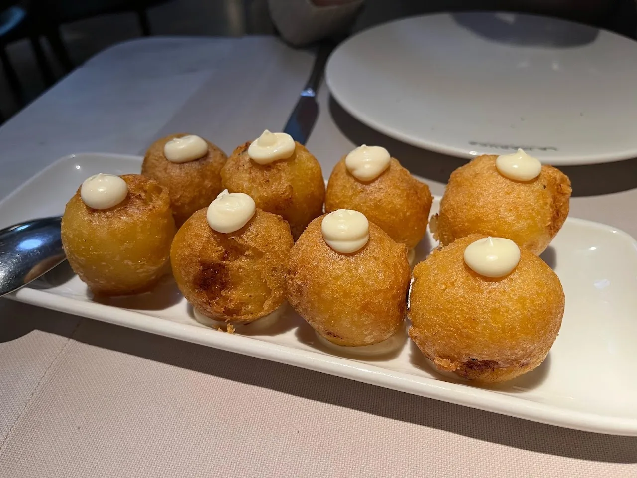 A row of small fried dough balls topped with cream
