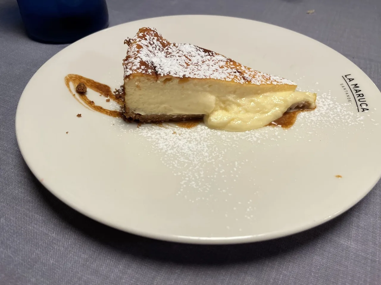 A slice of cheesecake dusted with icing sugar on a plate