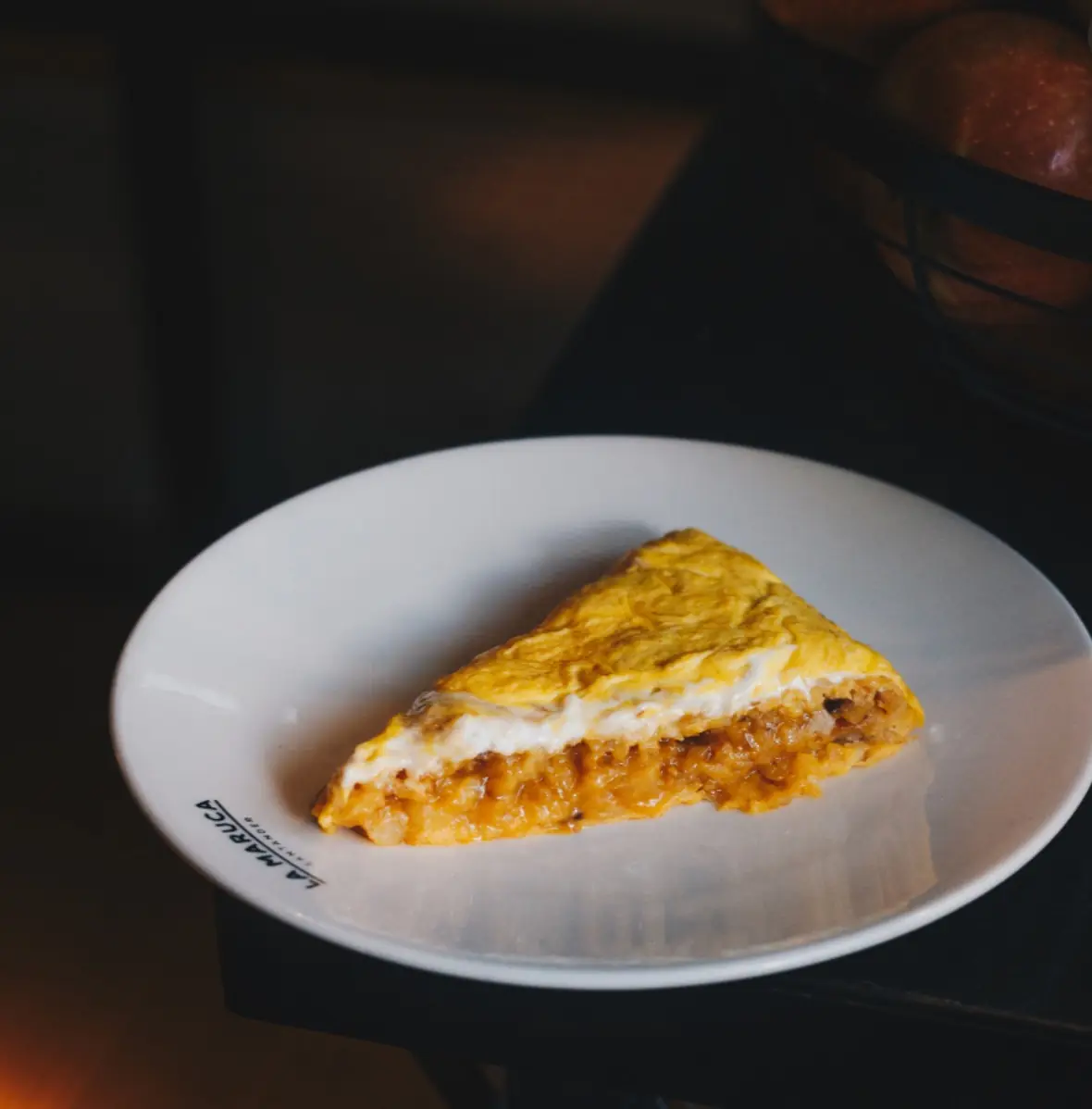 Wedge of Spanish tortilla with caramelized onion filling on a white plate