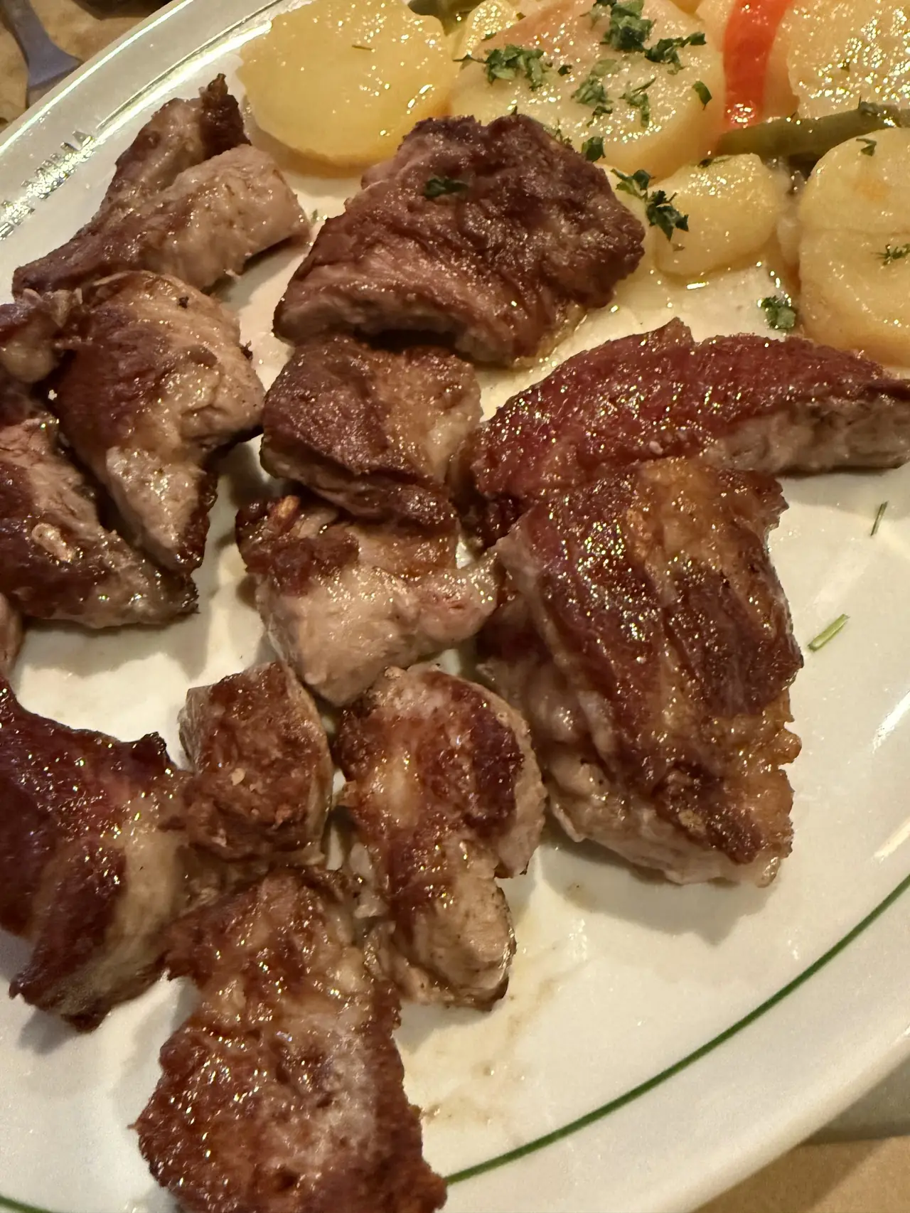 Grilled meat chunks with roasted potatoes and herbs on a plate