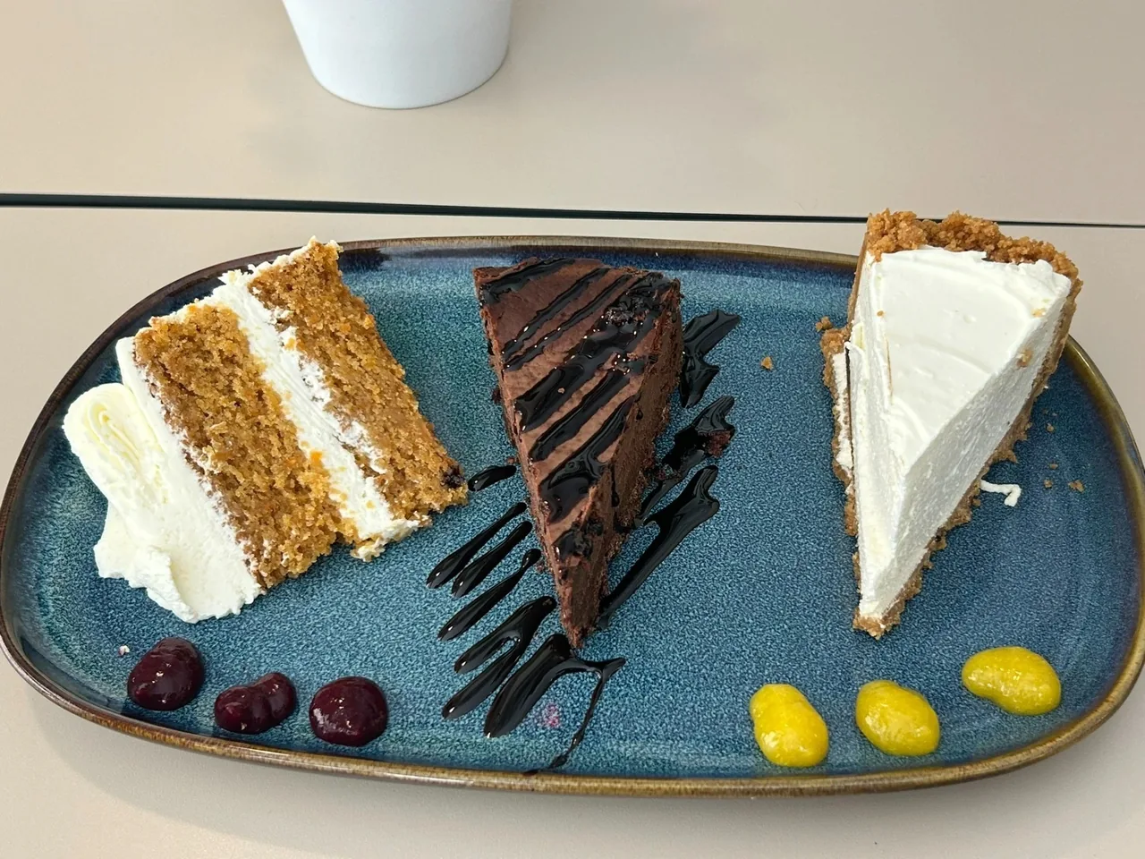 Three slices of cake on a blue serving plate with berries