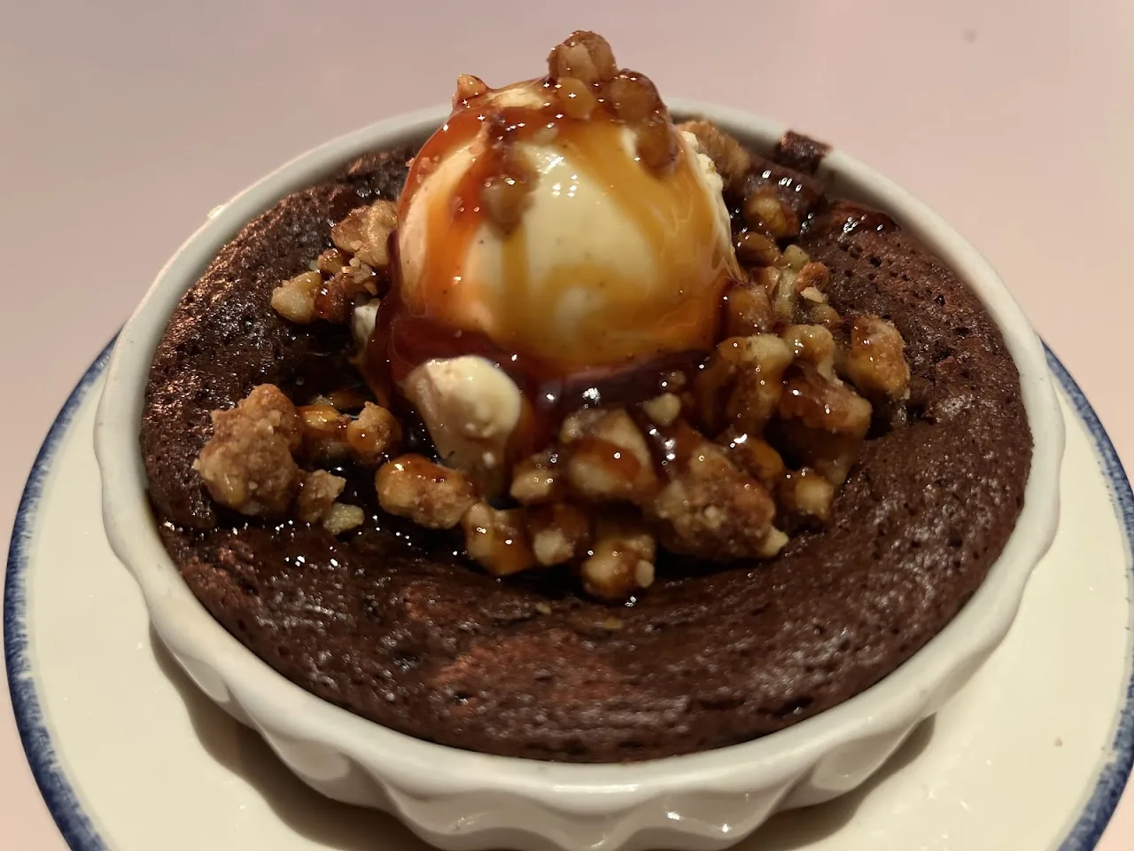 A chocolate dessert topped with a scoop of ice cream and crumbled nuts