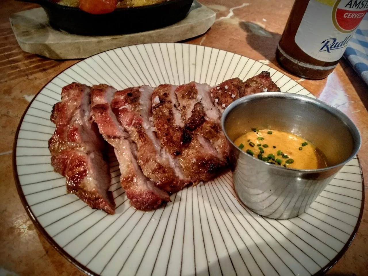 Sliced grilled meat served with a small cup of dipping sauce