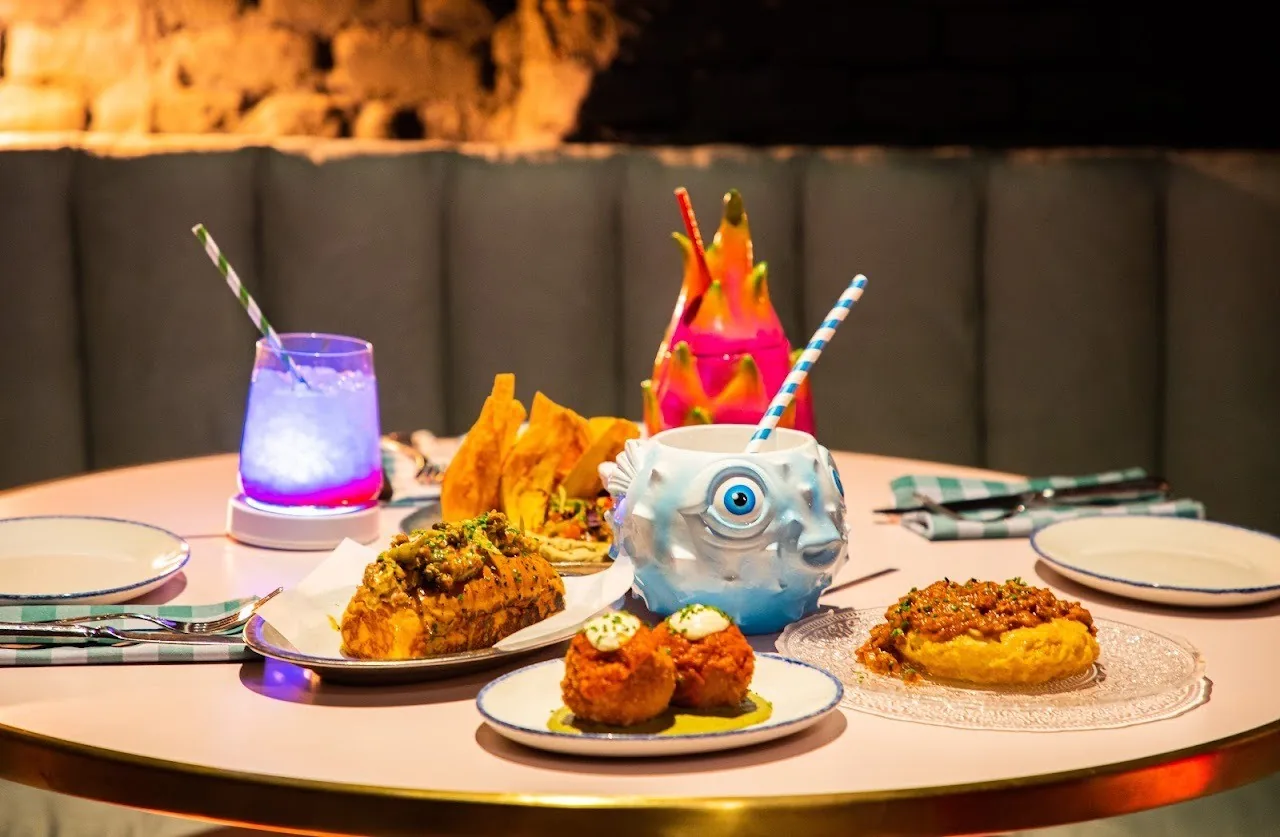 A table set with several small plates of food and a colourful cocktail