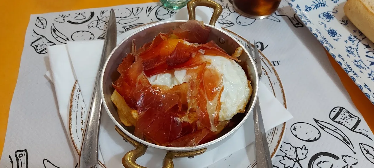 A poached egg dish with slices of ham in a metal pot