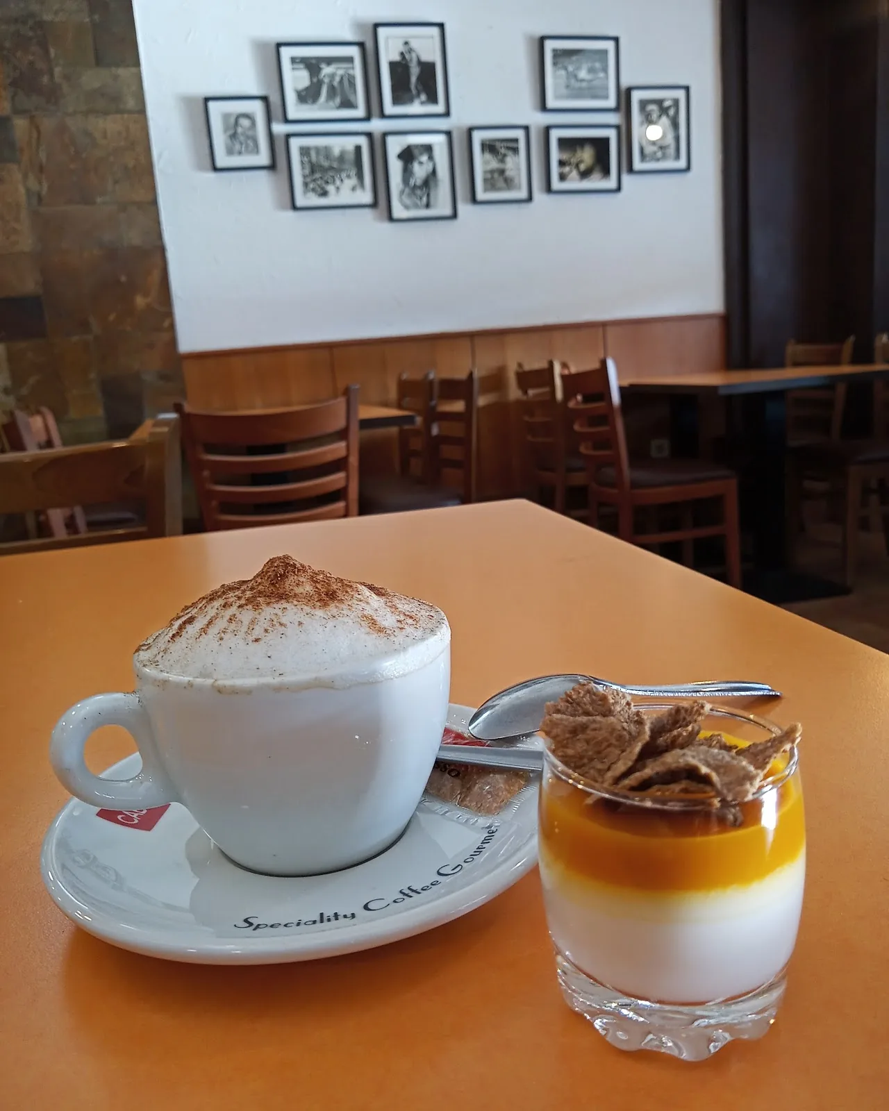 A cappuccino and a layered dessert in a glass on a table