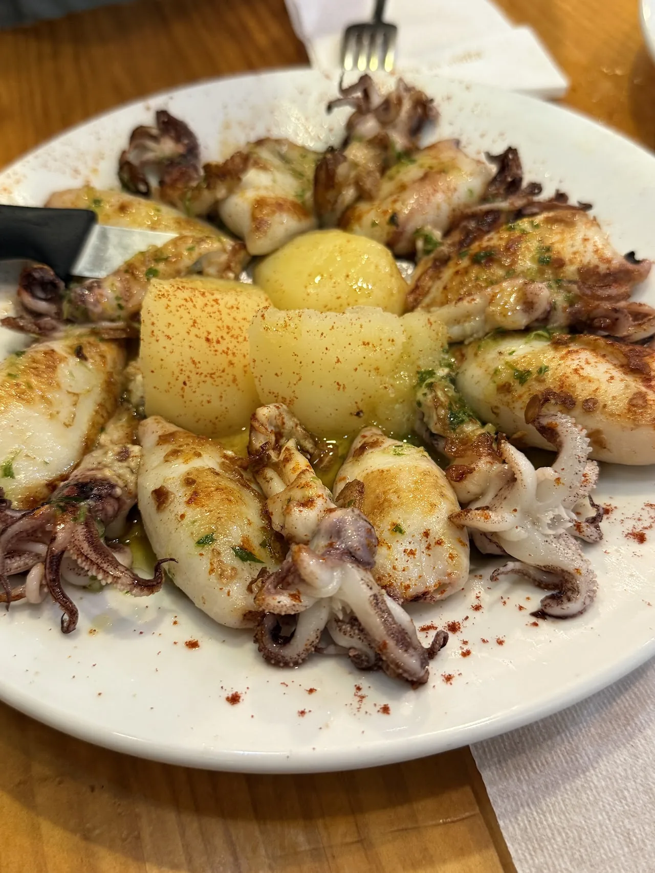 Grilled squid rings arranged around a piece of potato