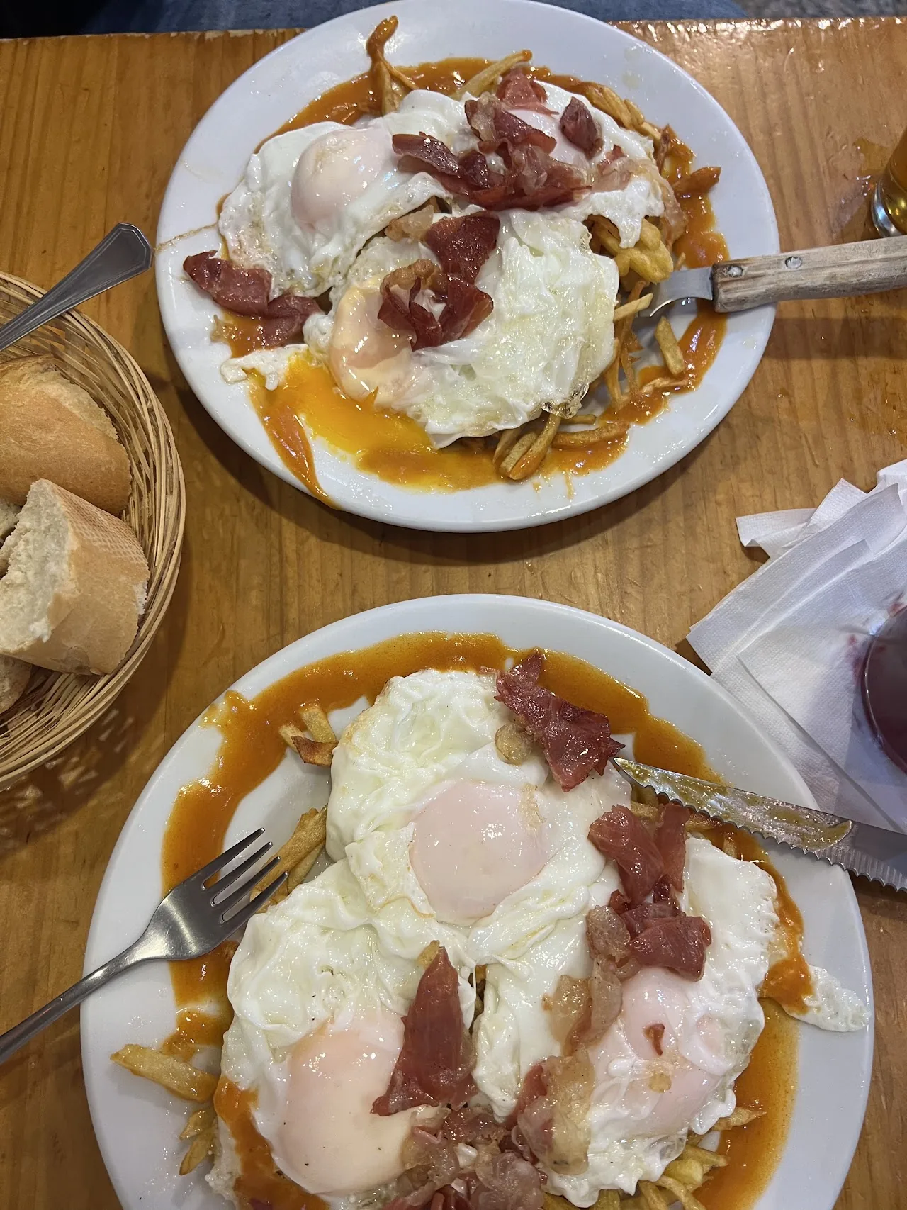 Two plates of fried eggs topped with ham and a fried garnish