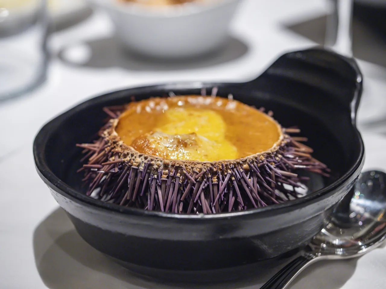 A sea urchin shell with a golden filling in a black pan