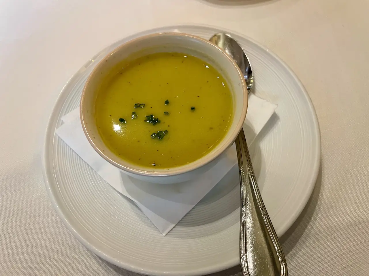 Bowl of green soup garnished with chopped herbs, served in a small cup with a spoon