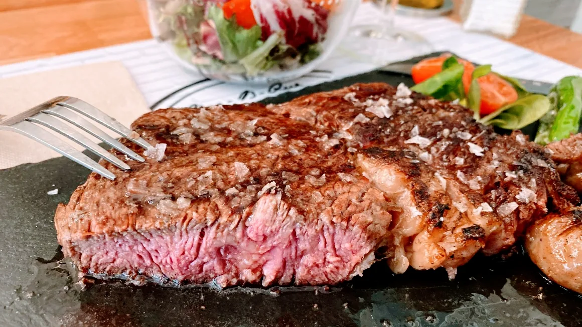 A seared steak with grill marks served with a side salad