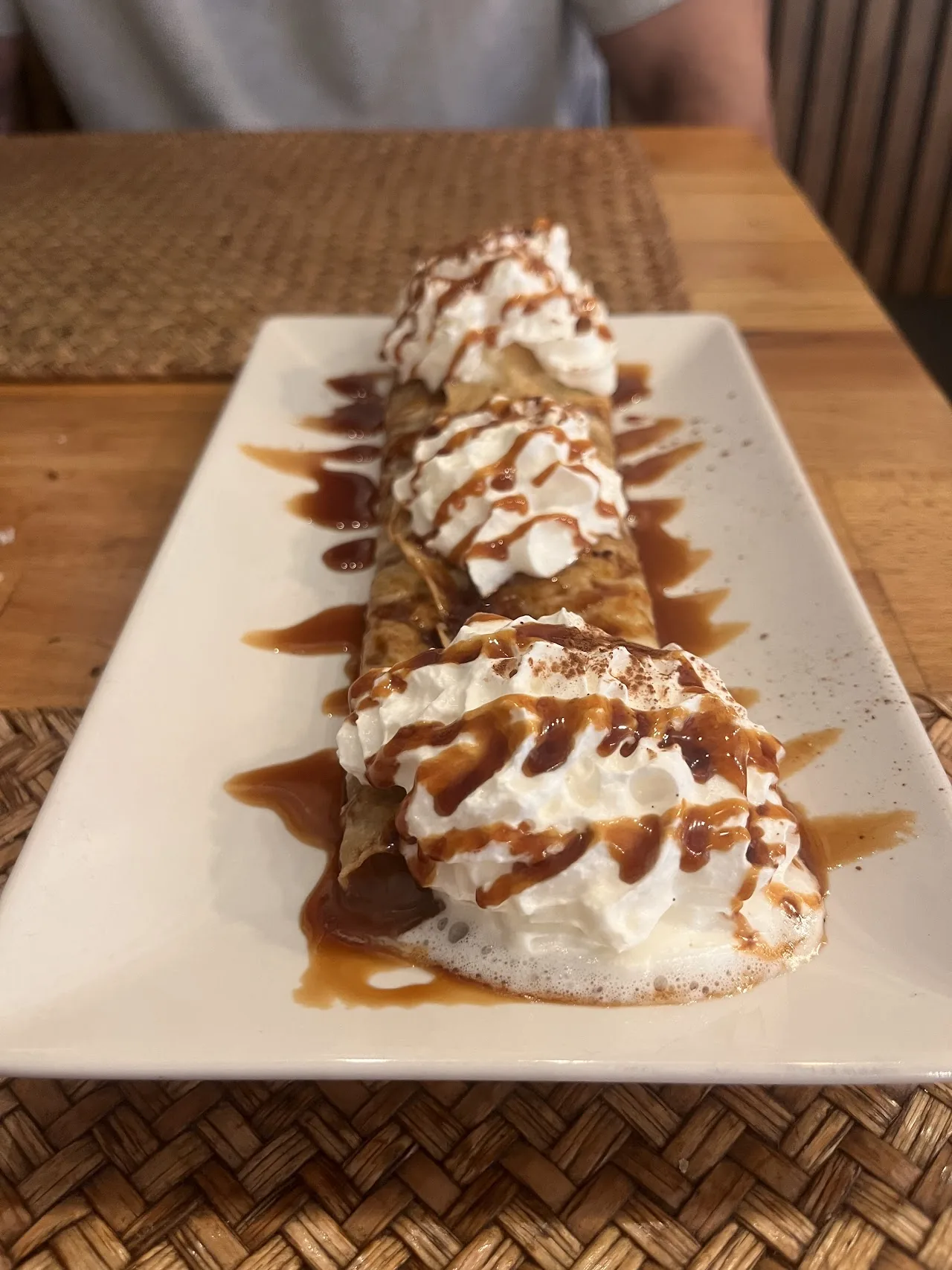 A dessert crepe topped with whipped cream and caramel drizzle