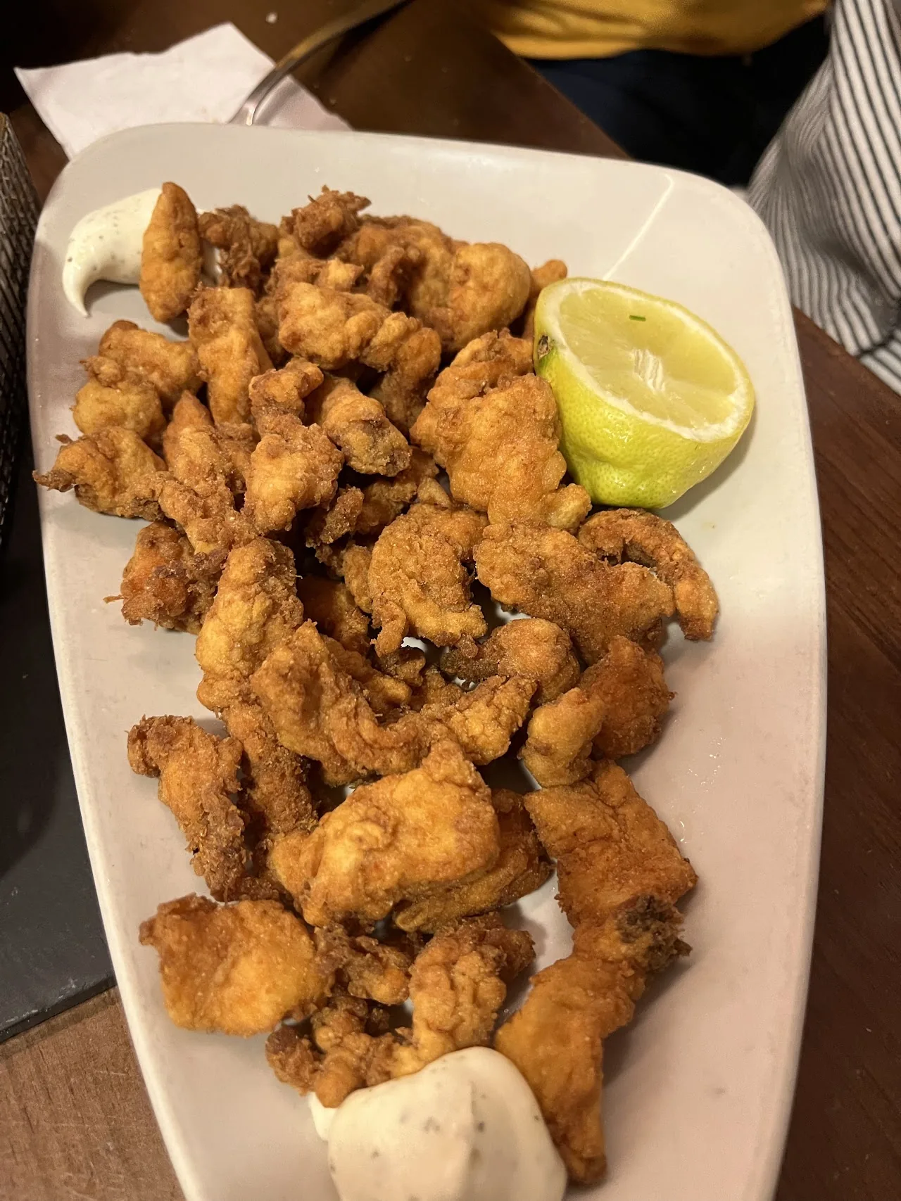 A plate of fried chicken or calamari pieces with a lemon wedge
