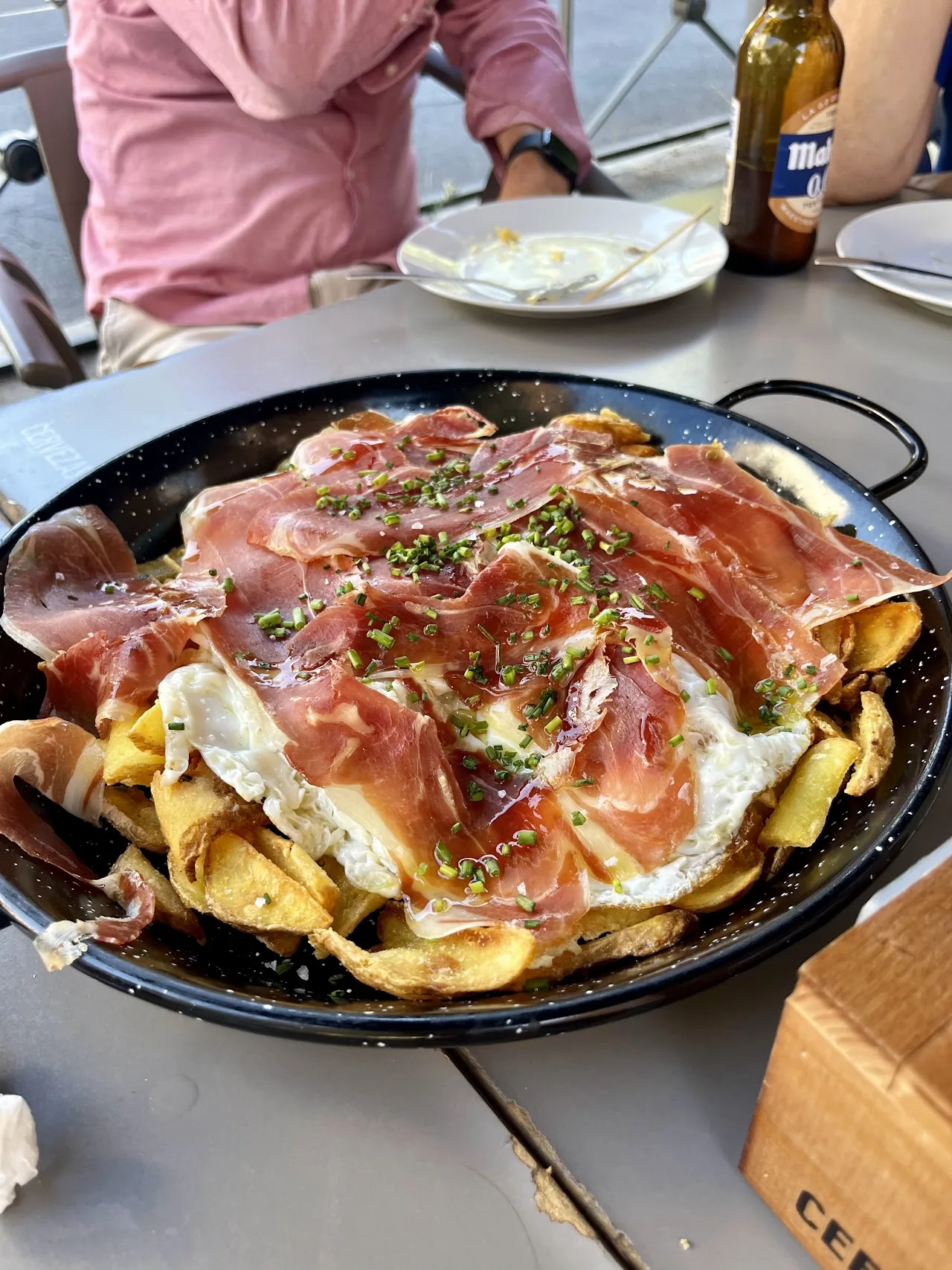 A pan of fries topped with a fried egg and ham slices