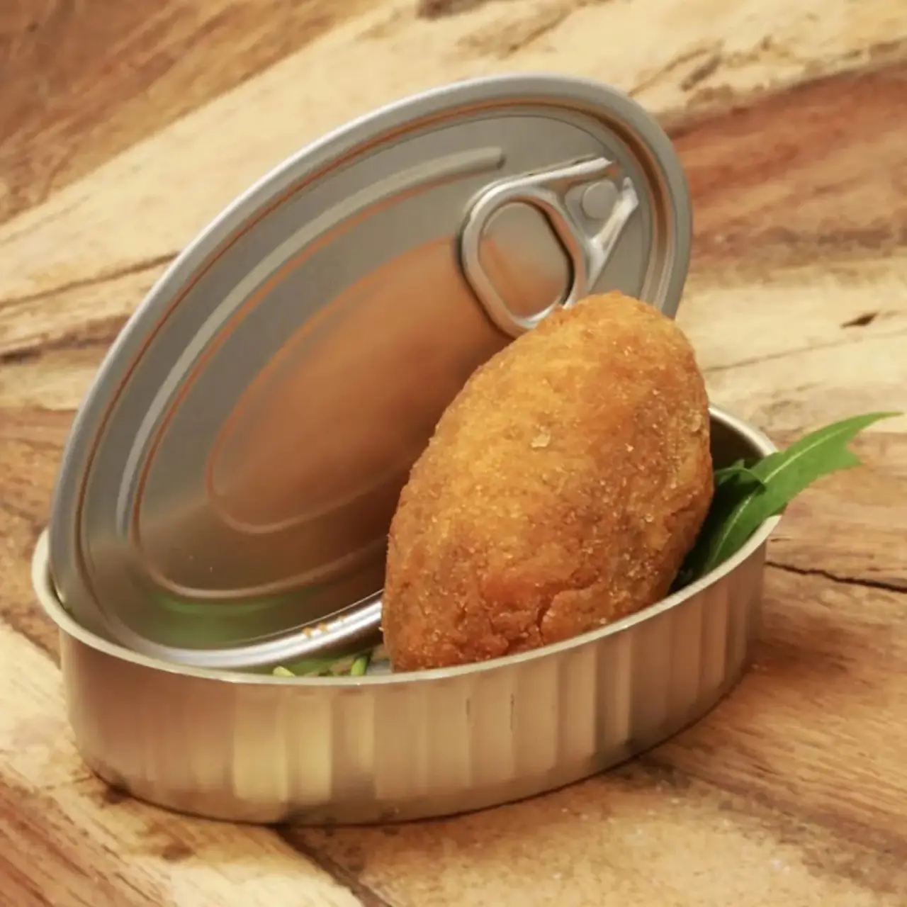 Breaded vegan croqueta served in an open tin can with a sprig of greens at La Perra Verde