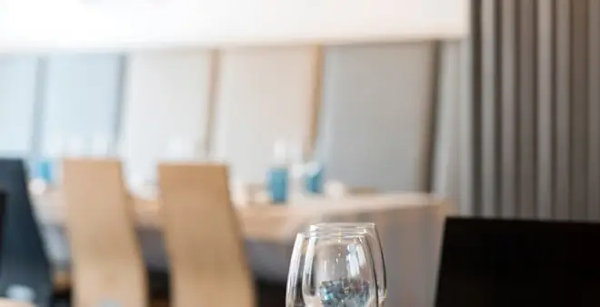 Dining room interior with set tables, wooden chairs and a wine glass in the foreground