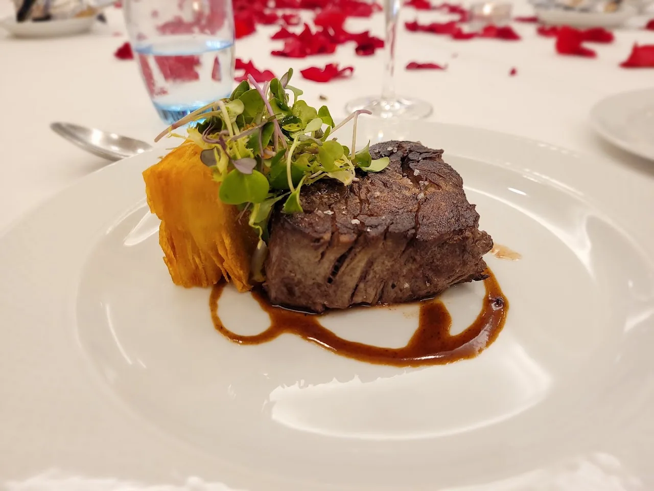 A seared steak with a slice of pumpkin on a white plate