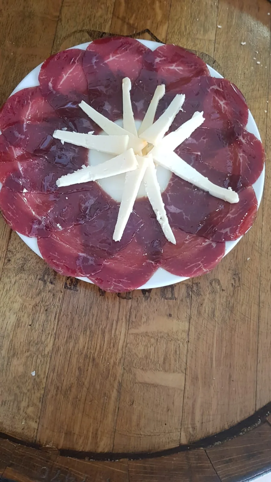 Thin slices of beef carpaccio arranged in a circle with garlic slivers