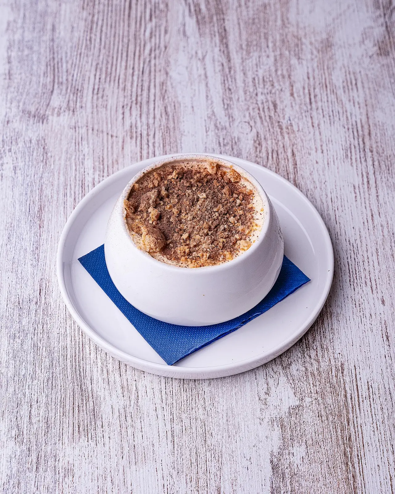 Tiramisu-style dessert with cocoa and crumble topping in a small cup
