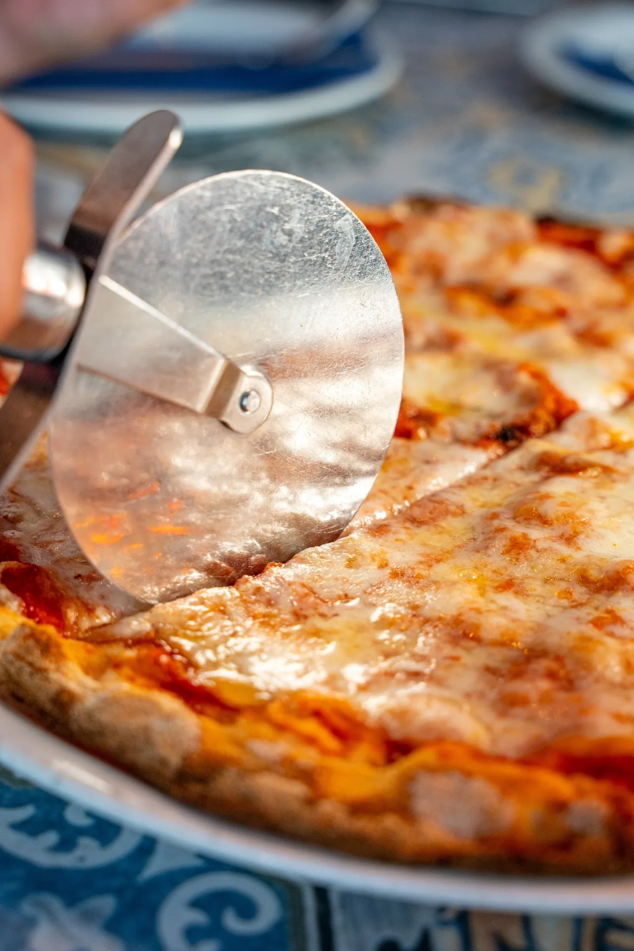 A close-up of a pizza with melted cheese and a pizza cutter resting on it