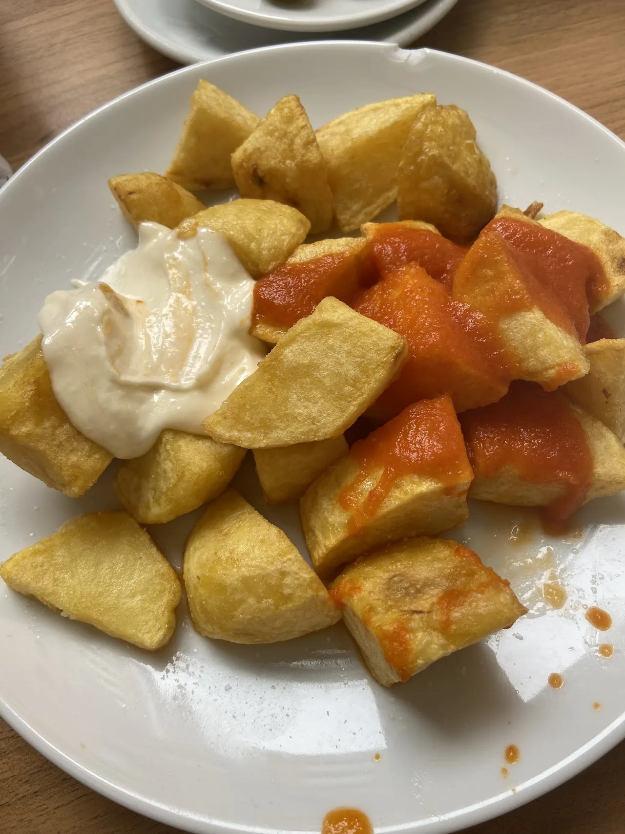 A plate of patatas bravas with spicy tomato sauce and aioli
