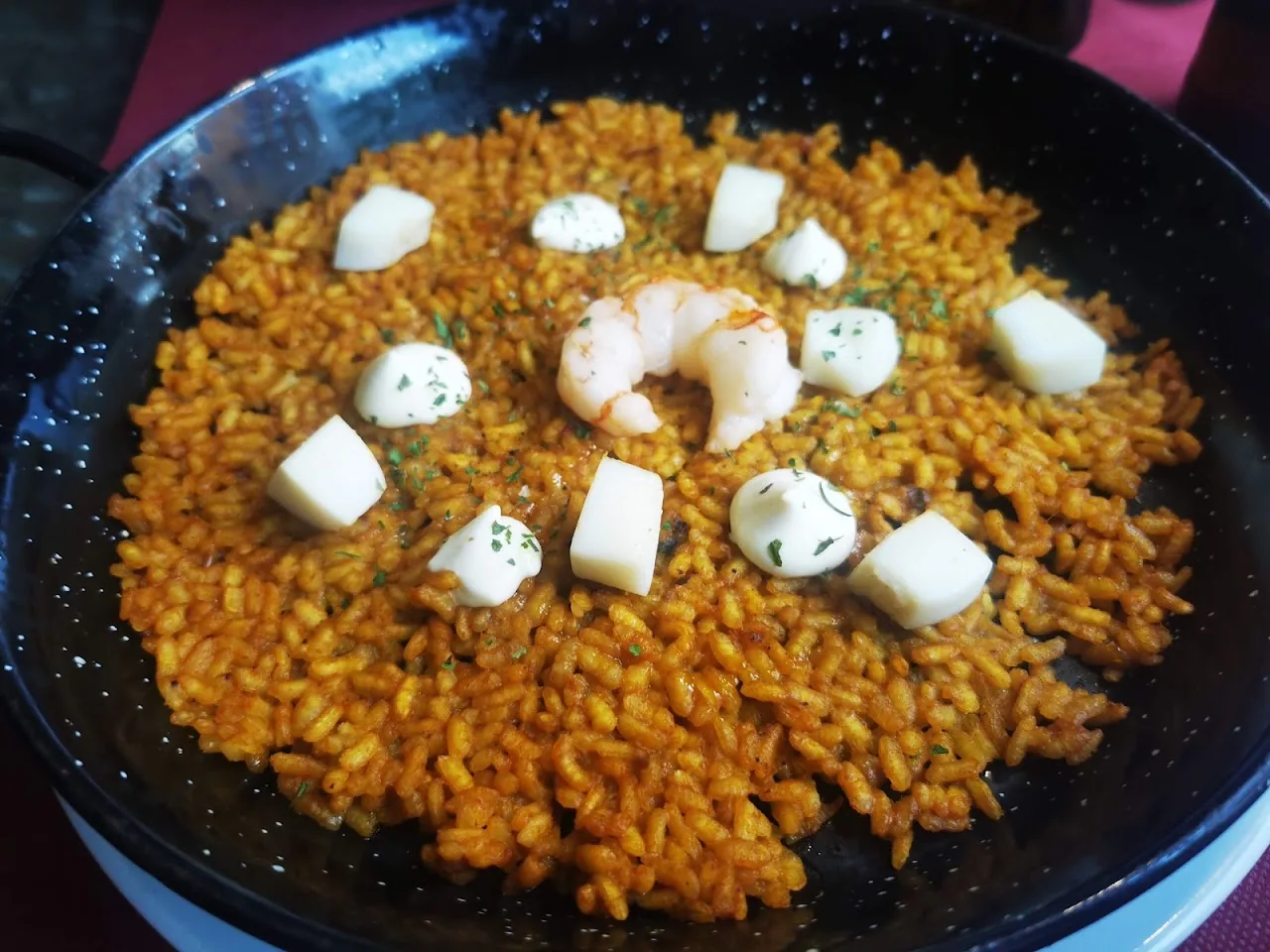 A paella-style rice dish topped with shrimp and diced cheese