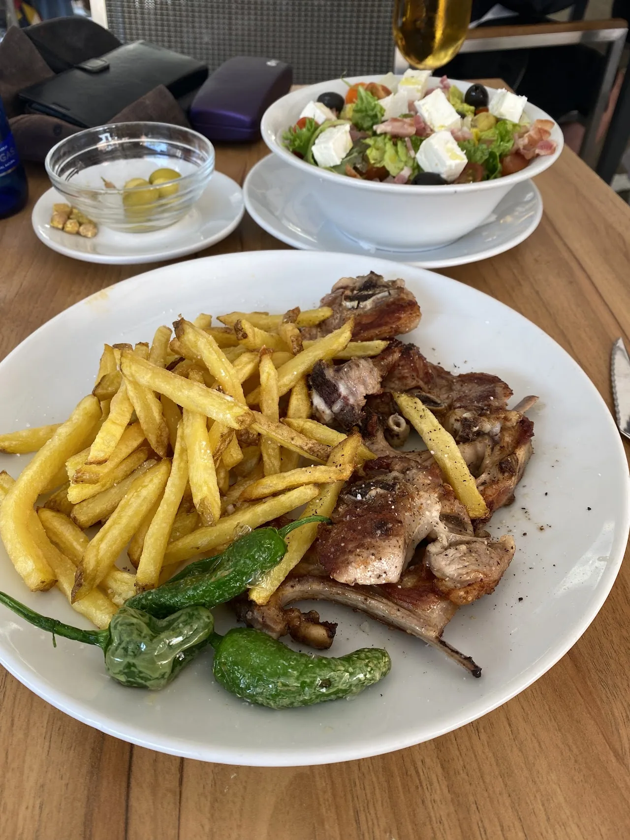 A plate of grilled meat with french fries and roasted green peppers