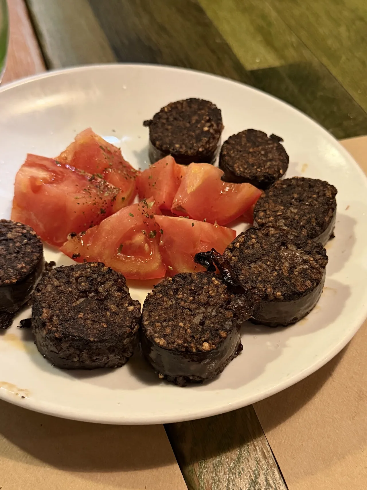 Sliced morcilla sausage with tomato wedges on a plate