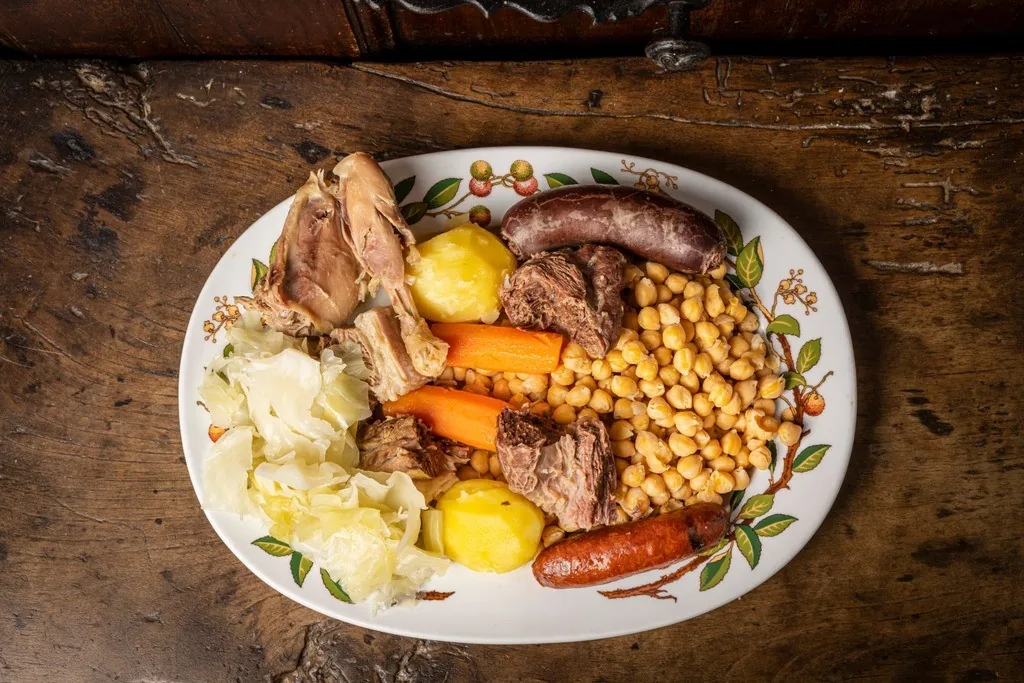 A platter of chickpeas, vegetables, meats and sausages