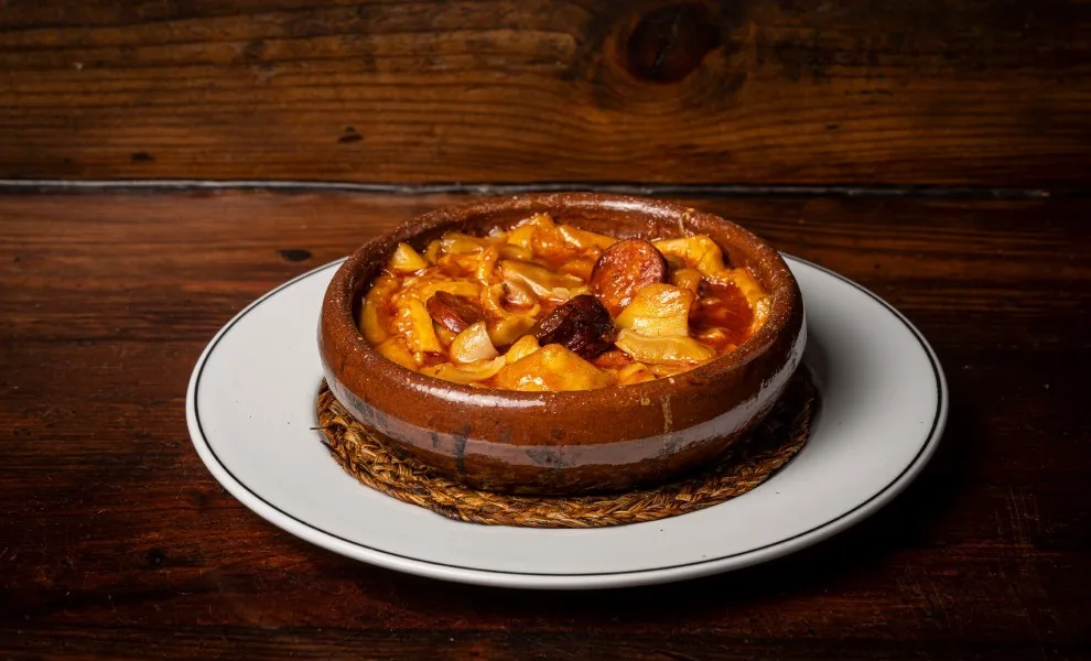 A round earthenware bowl of stew on a white plate