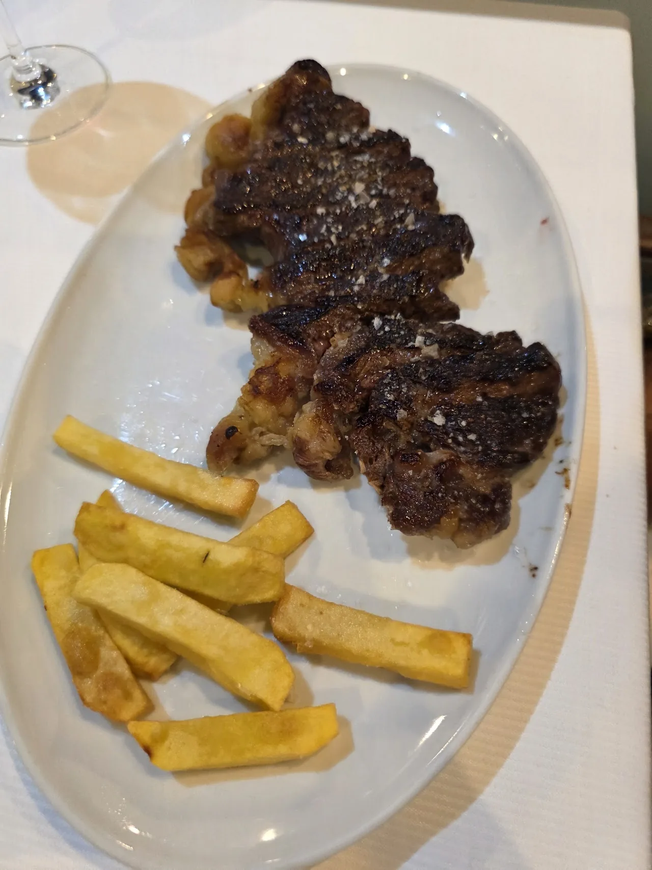 Grilled meat slices with french fries on a white plate