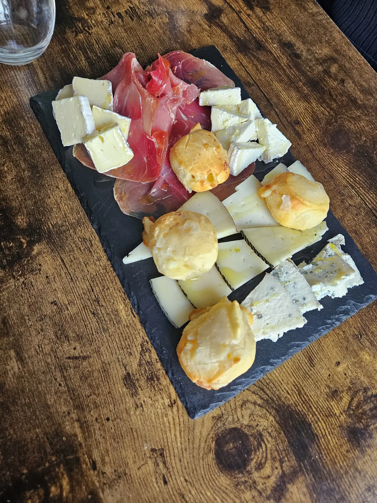 Slate board of cured ham, assorted cheeses and cheese puffs