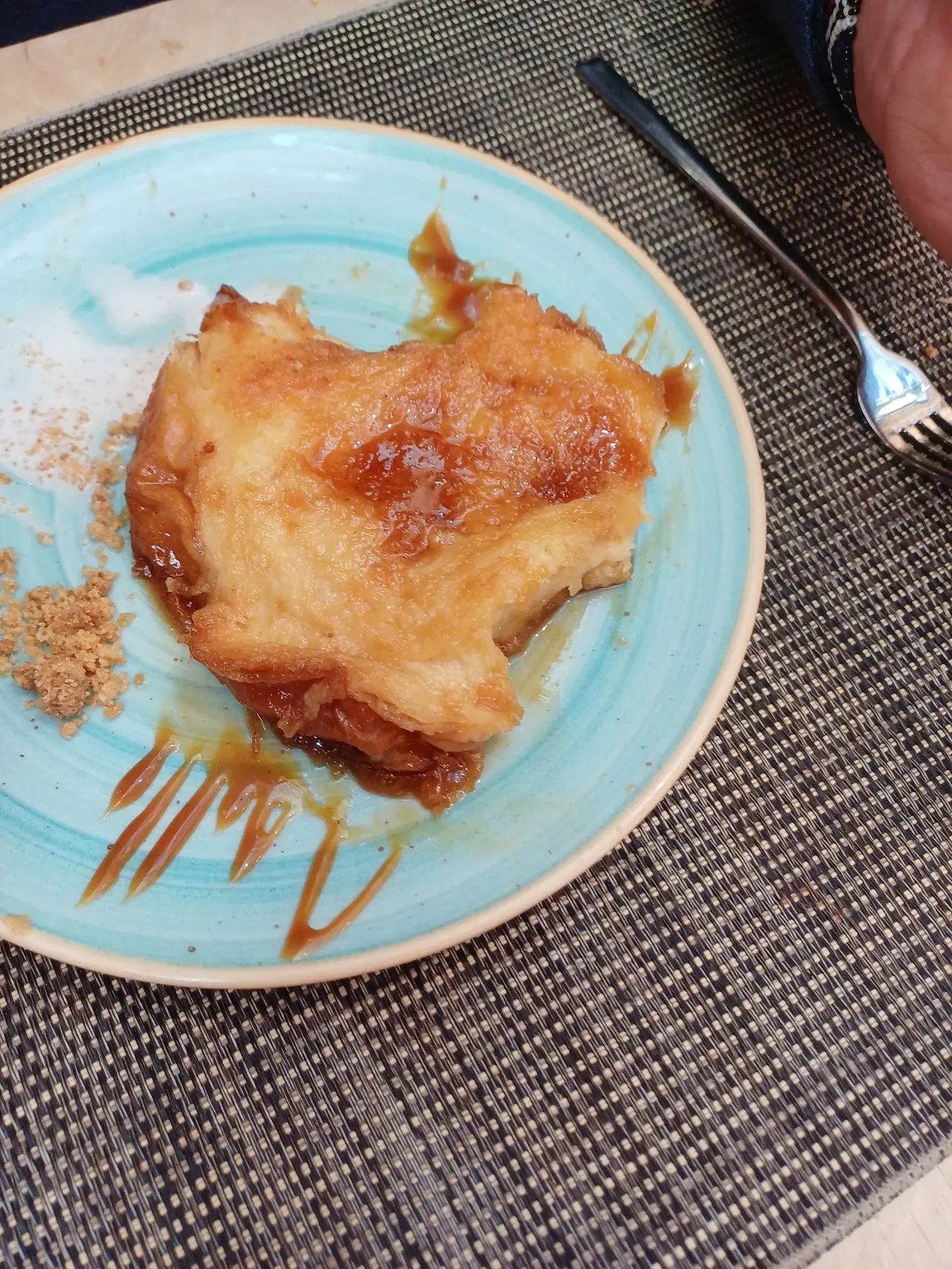 Caramel-glazed pastry dessert with caramel sauce drizzled on a blue plate