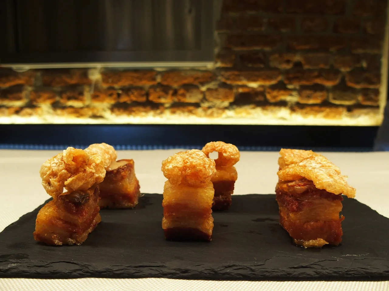 Four crisp pieces of pork on a dark slate board
