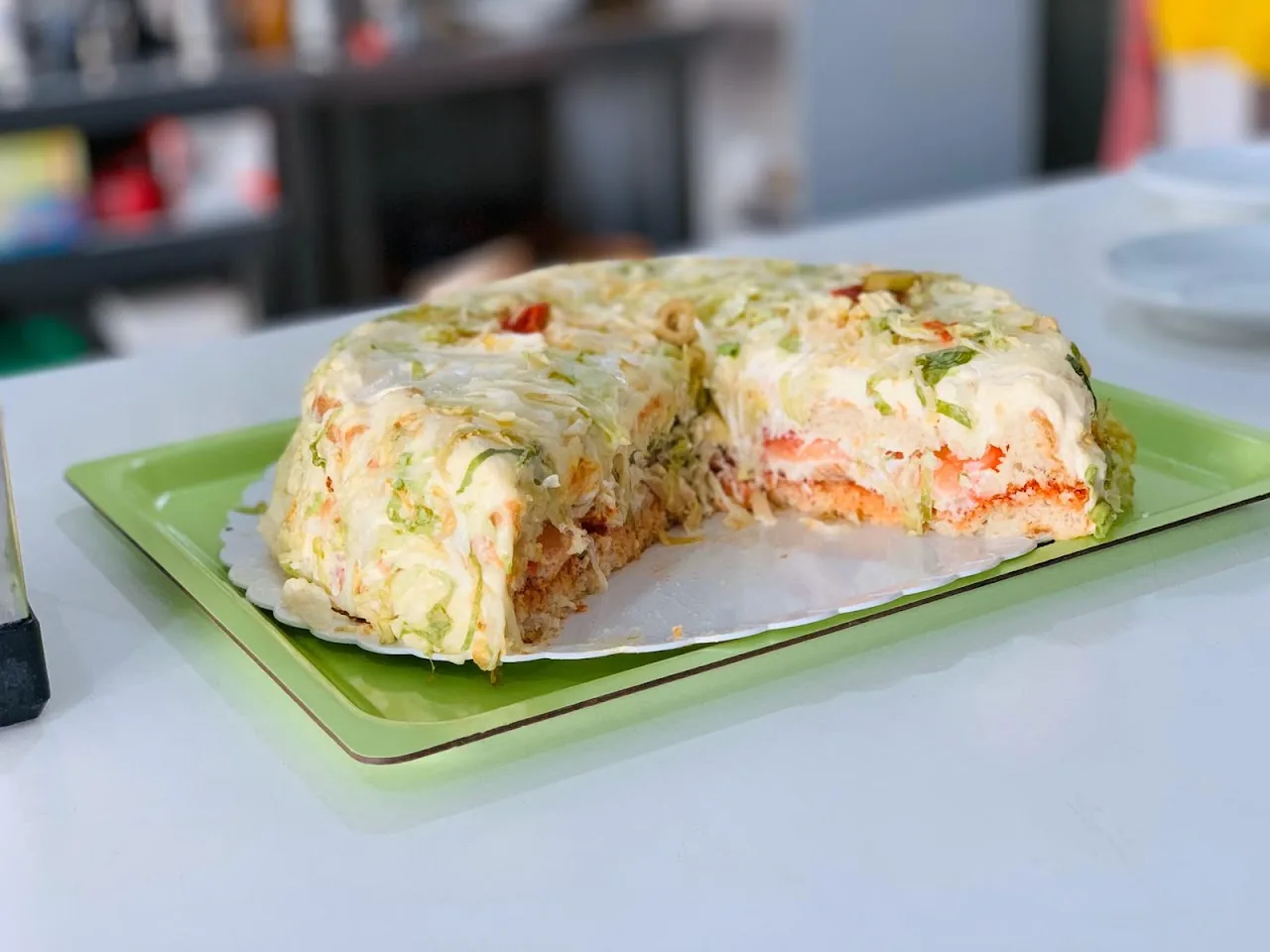 A layered savory sandwich cake on a green tray