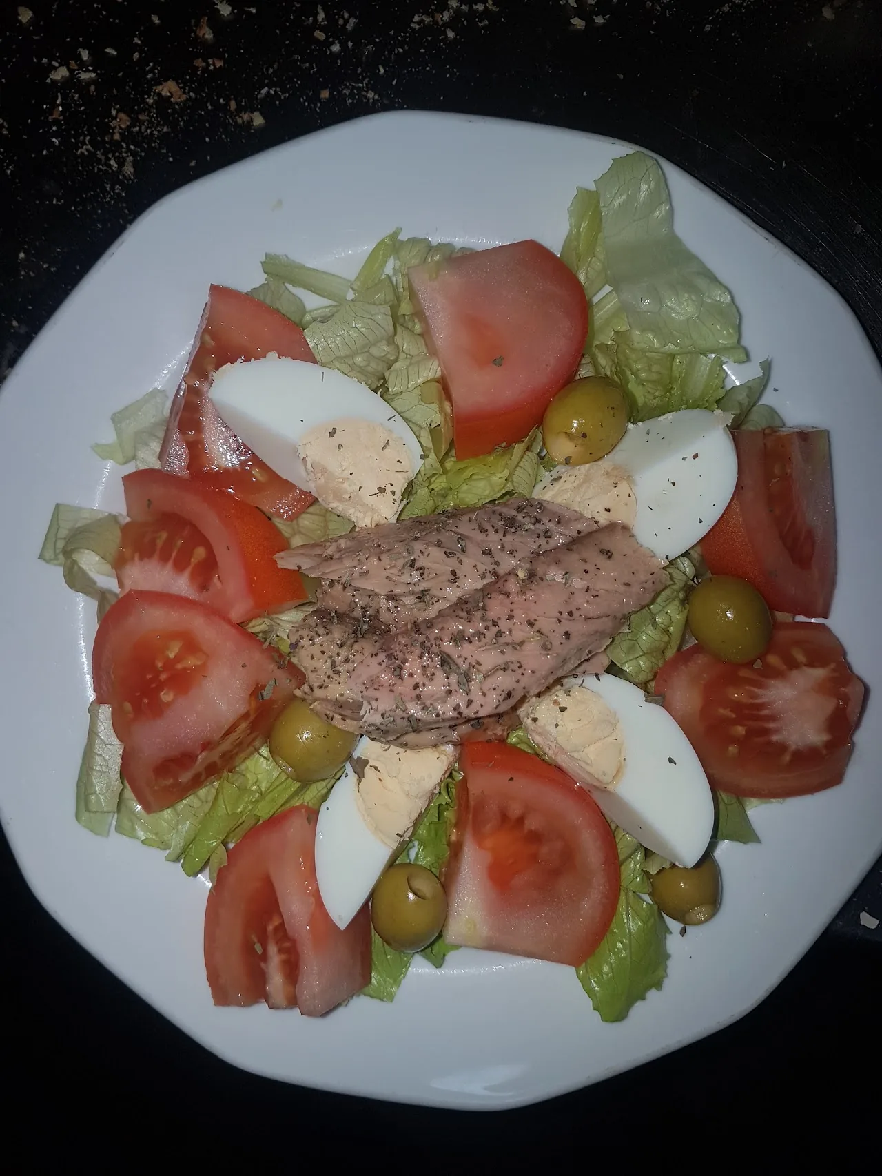 A salad with tuna, boiled egg, tomato and olives