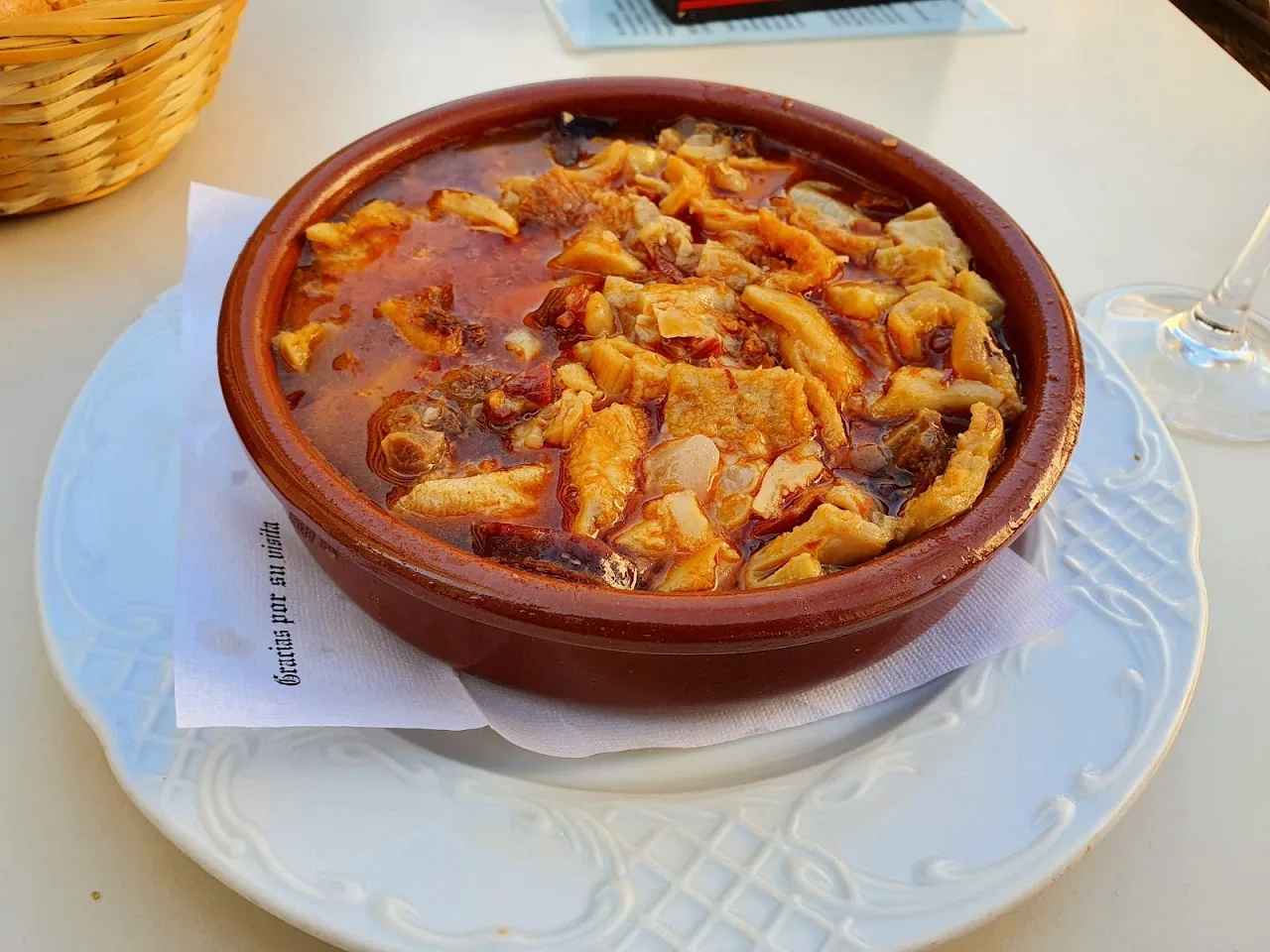 A clay dish of stewed potatoes with meat in tomato sauce