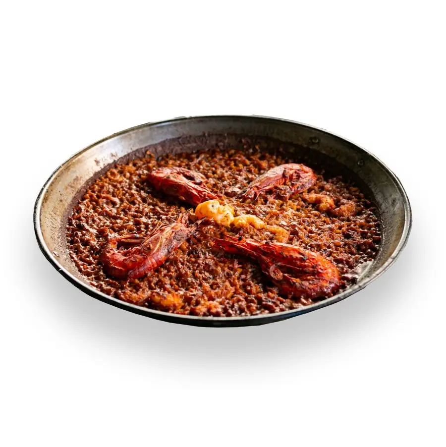Dark seafood rice with whole red prawns in a paella pan on a white background