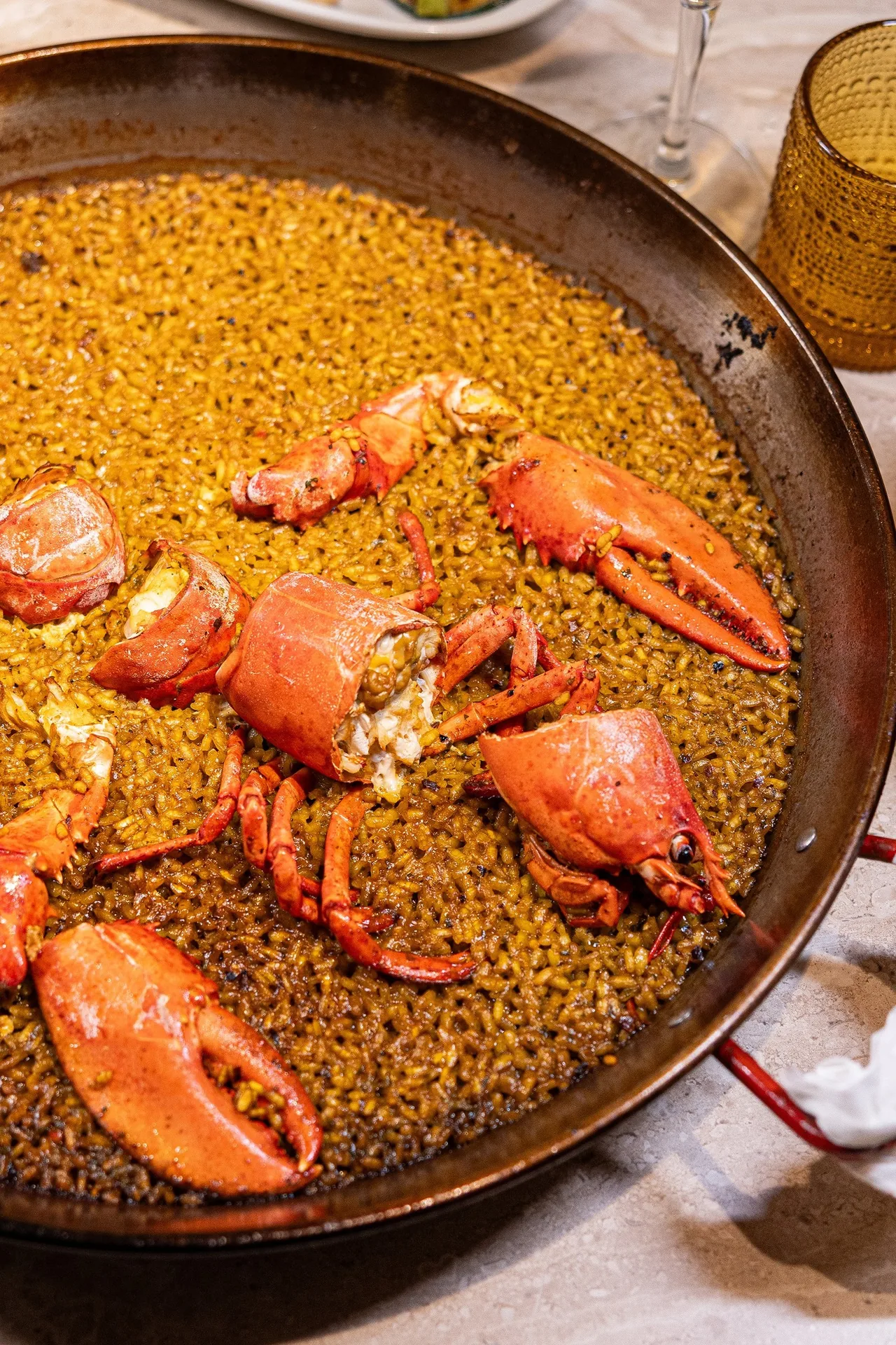 Overhead view of a lobster paella in a black pan at La Taberna de Peñalver