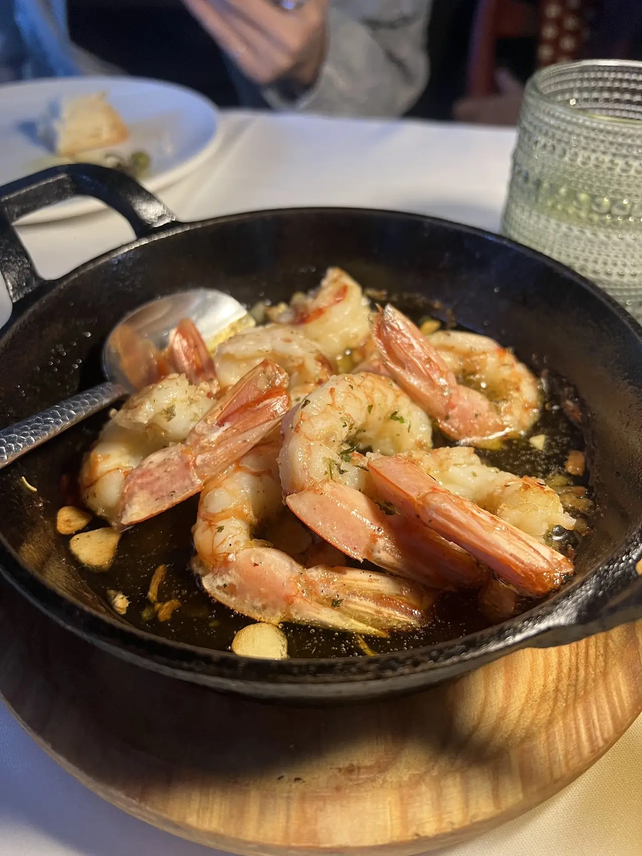 Garlic shrimp sizzling in olive oil in a cast-iron pan.