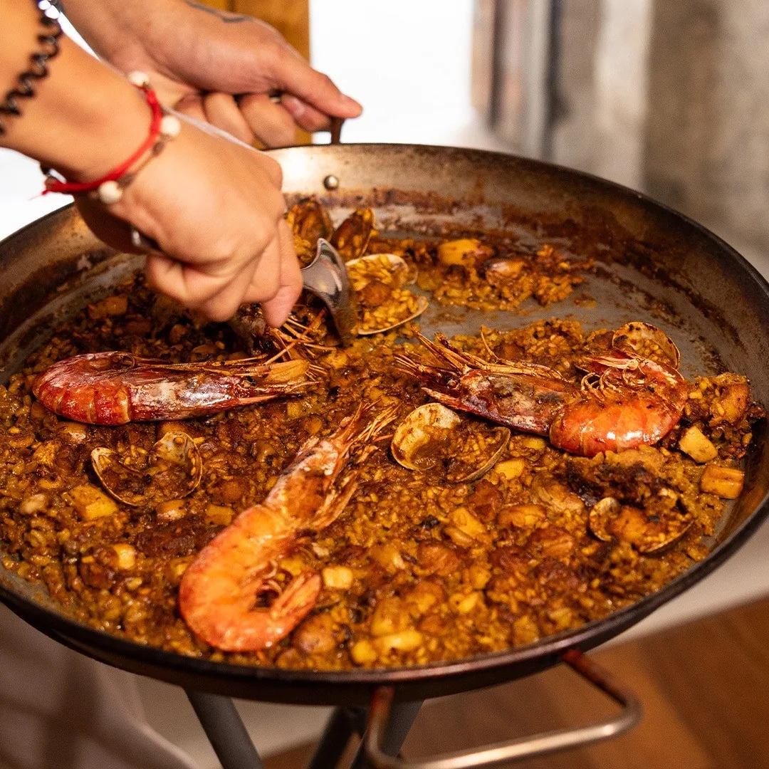 A paella with carabinero prawns being served from the pan