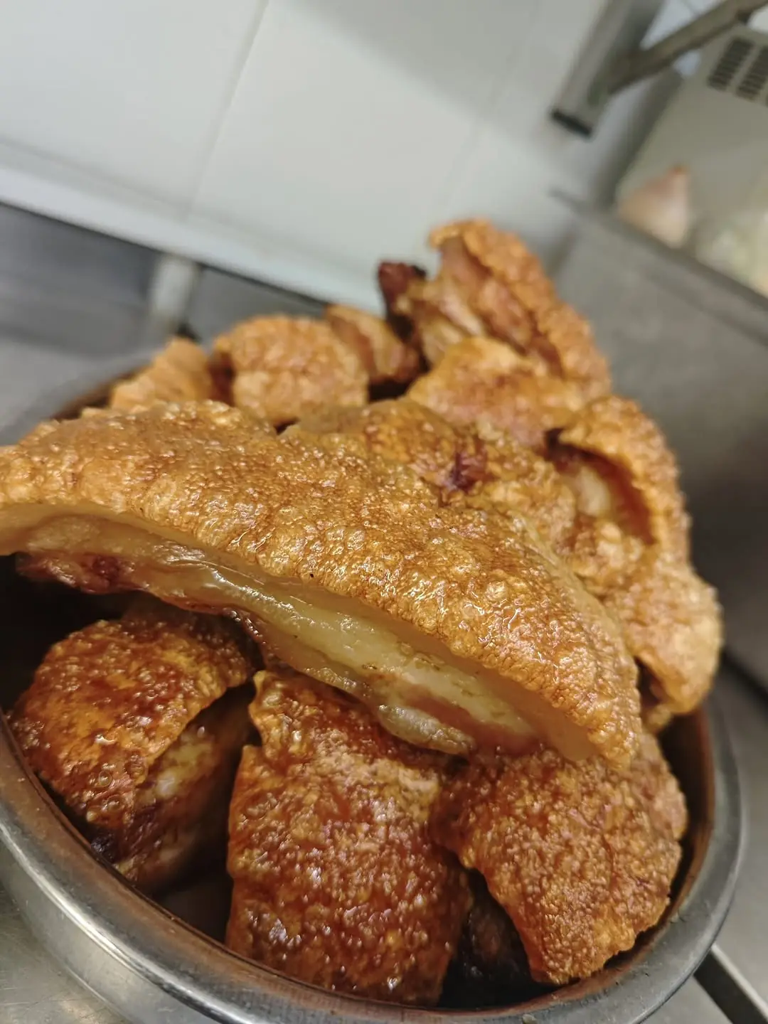Crispy torreznos, chunks of fried pork belly with crackling, in a metal serving bowl