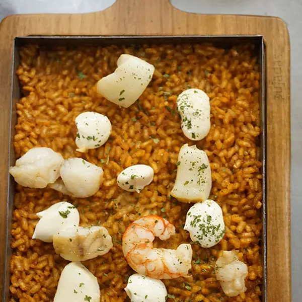 Arroz a banda in a metal tray, topped with pieces of squid and prawns